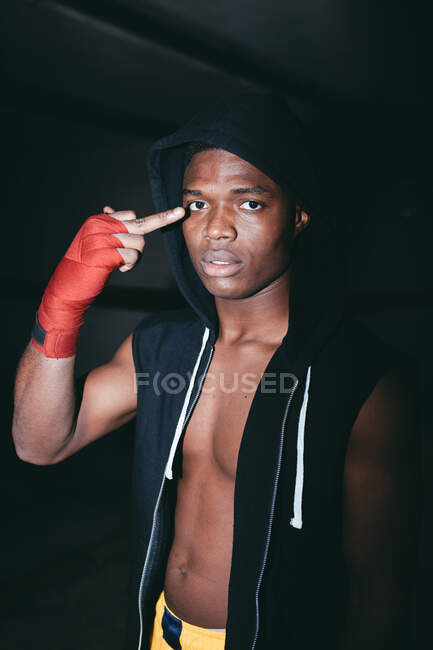 Joven atleta masculino afroamericano grosero con capucha demostrando el dedo medio y mirando a la cámara - foto de stock