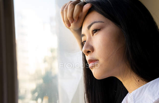 Visão lateral da jovem executiva étnica olhando para a janela no espaço de trabalho — Fotografia de Stock