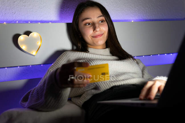 Teenager im Pullover tippt beim Online-Shopping Kreditkartendaten auf die Tastatur des Netbooks — Stockfoto
