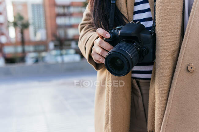 Recortado fotógrafa irreconocible fotografía de fotos en la cámara de fotos profesional en la calle de la ciudad - foto de stock