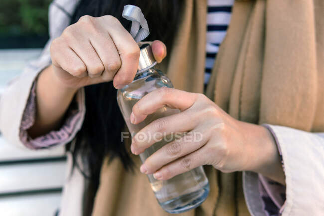 Crop anonymous female opening glass bottle made of eco friendly glass material for saving environment — Stock Photo