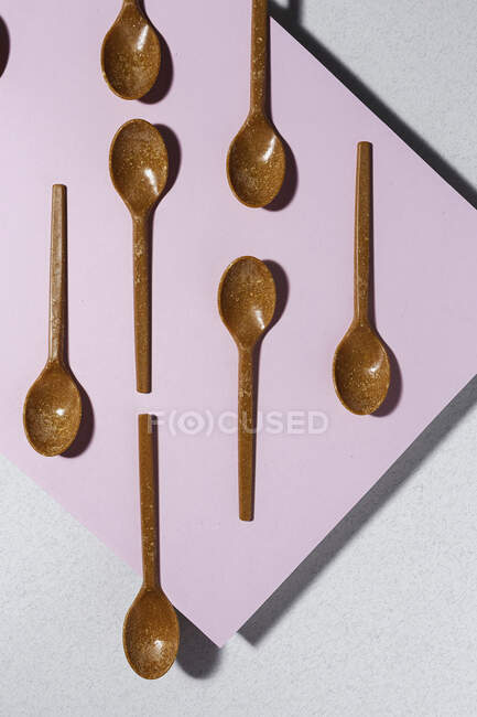Vista aerea di cucchiai eco friendly marrone su sfondo rosa e bianco — Foto stock