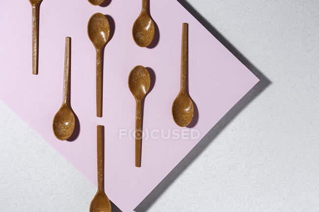 Overhead view of brown eco friendly spoons on pink and white background — Stock Photo
