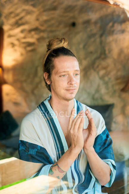 Young male with Namaste hands looking old building while practicing yoga in summer — Stock Photo