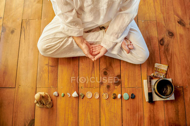 Von oben nicht wiederzuerkennender barfüßiger Mann praktiziert Yoga auf dem Boden in der Nähe von Schüsselgong und Buddha-Statuette — Stockfoto