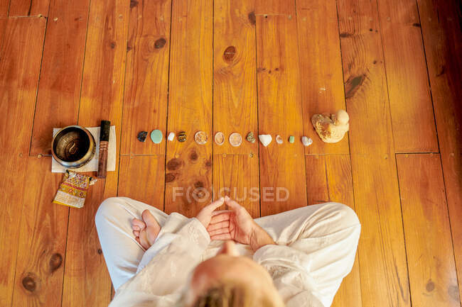 From above of crop unrecognizable barefoot male practicing yoga on floor near bowl gong and Buddha statuette — Stock Photo