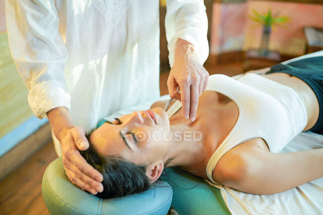 Crop male practitioner healing female patient with palm technique for recovering soul and body — Stock Photo