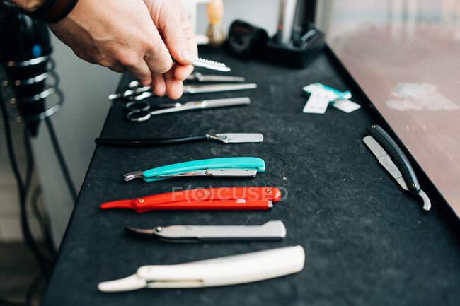 Crop анонімний майстер краси з колекцією бритв і ручних інструментів за столом в перукарні — стокове фото
