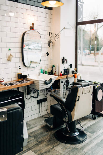 Table with assorted cosmetic products in bottles and dispensers between washstands under mirrors reflecting barbershop — Stock Photo