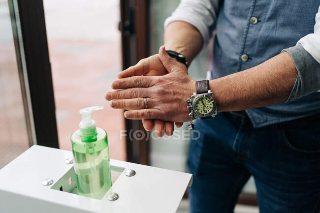 Ernte anonymen männlichen Friseur in Armbanduhr Anwendung antibakterielles Gel auf die Hände bei der Arbeit in Schönheitssalon — Stockfoto