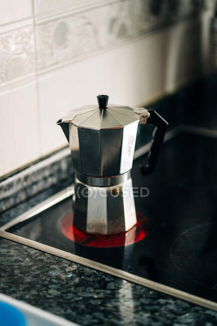 Metal stove top coffee maker with plastic handle on modern hot hob in house kitchen in daylight — Stock Photo