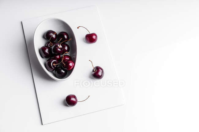 High angle of healthy ripe tasty cherries in ceramic bowl placed on white board — Stock Photo