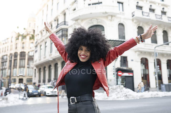 Femme noire avec des cheveux afro dans la rue et souriant à la caméra — Photo de stock