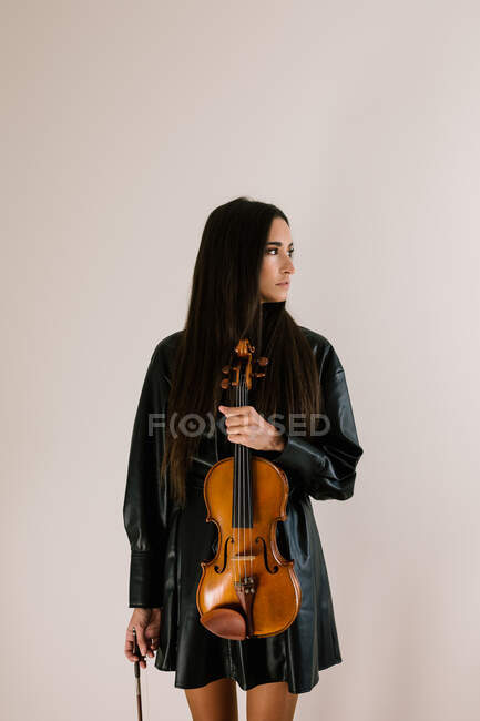 Violoniste féminine debout avec instrument de musique et détournant le regard — Photo de stock