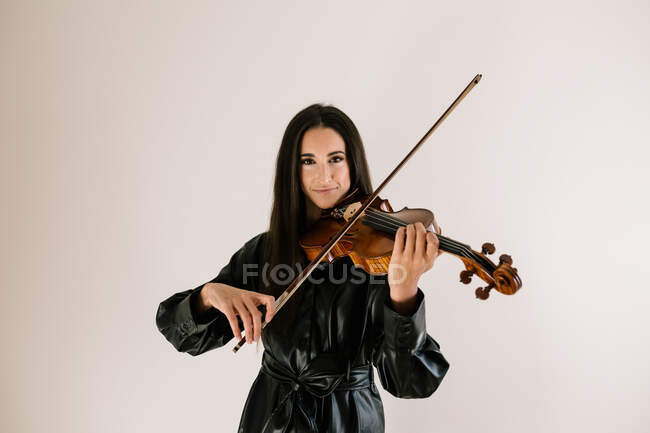 Smile artist playing stringed musical instrument while practicing skills standing against white background — Stock Photo