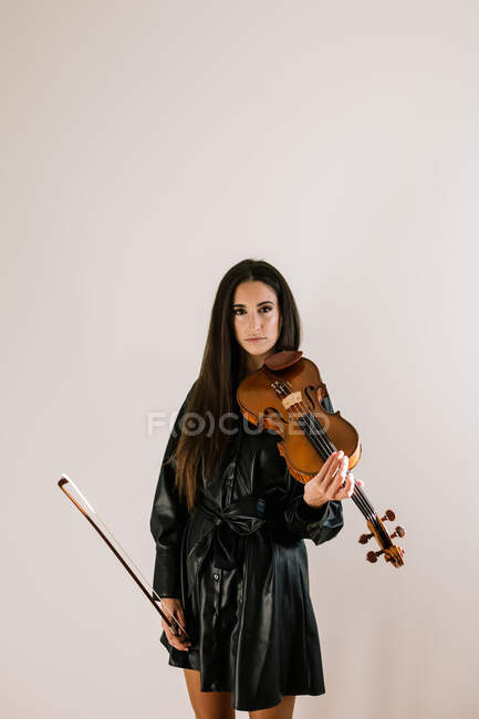 Artista sério tocando instrumento musical com cordas enquanto pratica habilidades em pé contra fundo branco — Fotografia de Stock