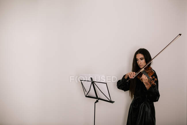 Artista serio che suona strumento musicale a corda mentre pratica abilità in piedi su sfondo bianco — Foto stock