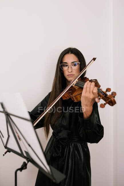 Серьезный художник играет на струнном музыкальном инструменте, практикуя навыки, стоящие на белом фоне — стоковое фото