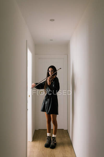 Serious artist playing stringed musical instrument while practicing skills standing against white background — Stock Photo