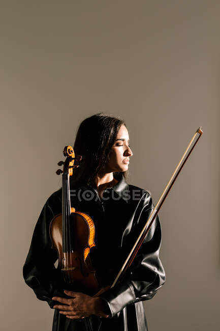 Жінка скрипалька стоїть з музичним інструментом і задумливо закриті очі — стокове фото