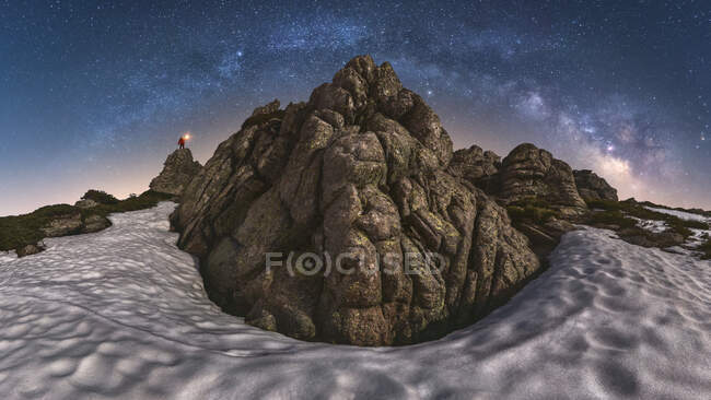 Viajante com lanterna em pé no penhasco da cordilheira no Parque Nacional Picos de Europa sob céu escuro estrelado noite — Fotografia de Stock