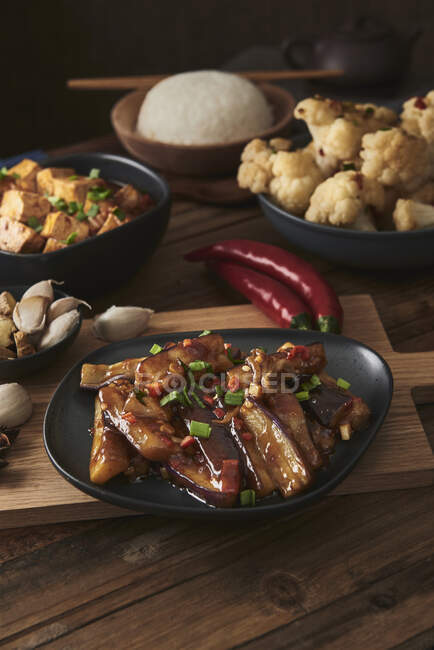 Mala tofu and yuxiang, chinese vegan dishes, accompanied by a bowl of rice, cauliflower, soy sauce and a Japanese teapot on top of a wooden table decorated with fabrics — Stock Photo