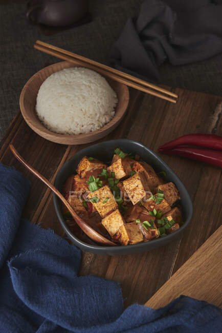 Close up mala tofu, chinese vegan dish, accompanied by a bowl of rice and a Japanese teapot on top of a wooden table decorated with fabrics — Stock Photo