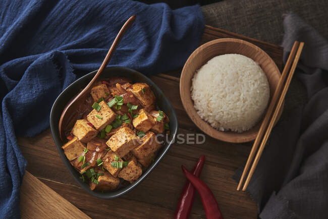 Gros plan tofu mala, plat végétalien chinois, accompagné d'un bol de riz sur une table en bois décorée de tissus — Photo de stock