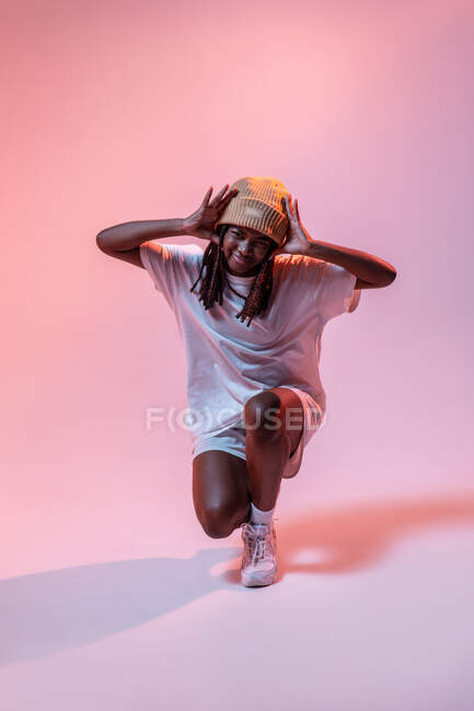 Тіло сконцентрованого афроамериканського підлітка танцює з витягнутими руками в студії з яскравим неоновим світлом. — стокове фото