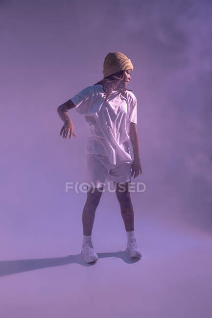 Full body of concentrated African American teen dancing in studio with bright neon light — Stock Photo
