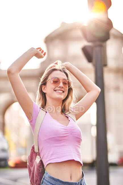 Happy female with hands raised standing in sunshine during trip in Madrid — Fotografia de Stock