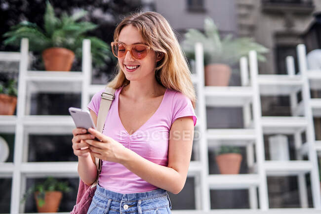 Веселая женщина просматривает мобильный телефон, стоя на улице Мадрида — стоковое фото