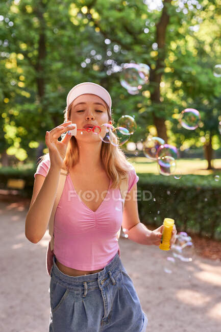 Femmina spensierata che soffia bolle mentre trascorre una giornata di sole nel parco verde di Madrid — Foto stock