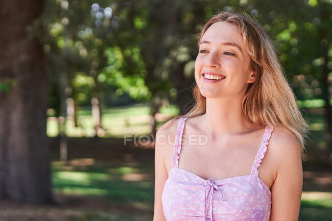 Donna sorridente che indossa un abito estivo nel parco con alberi verdi a Madrid — Foto stock