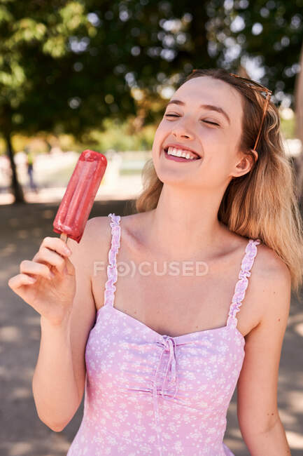 Mulher alegre em vestido de verão de pé com picolé e desfrutando de dia ensolarado em Madrid — Fotografia de Stock