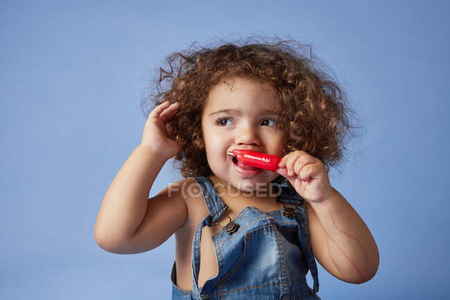 Petite fille bouleversée regardant loin debout avec de la crème glacée sur fond bleu studio — Photo de stock