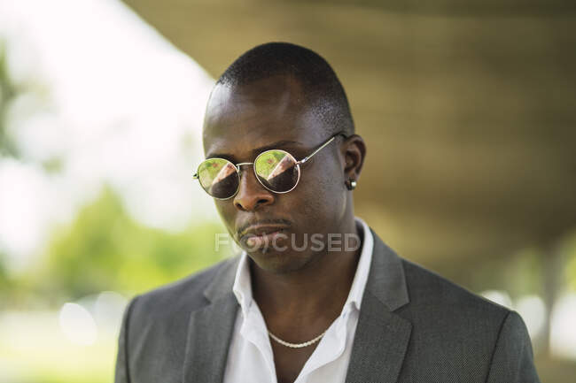 Adult African American male entrepreneur in formal clothes and chain with earring on blurred background in sunlight — Stock Photo
