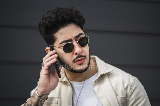 Focused bearded ethnic male in accessories and trendy apparel surfing internet on cellphone on street in daytime — Stock Photo
