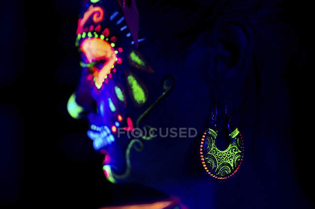 Анонімна жінка в різнокольоровій маскарадній масці з квітами на голові дивиться на ніч Хеллоуїна — стокове фото