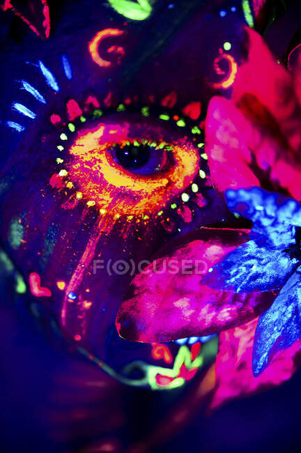 Mulher anônima em máscara de máscaras multicoloridas com flores na cabeça olhando para a câmera na noite de Halloween — Fotografia de Stock