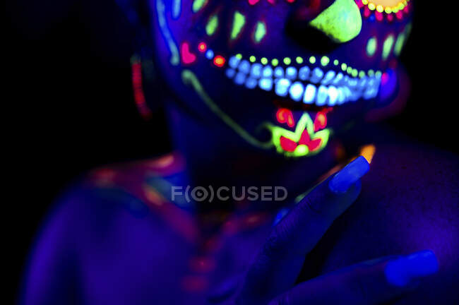 Mulher anônima em máscara de máscaras multicoloridas com flores na cabeça na noite de Halloween — Fotografia de Stock