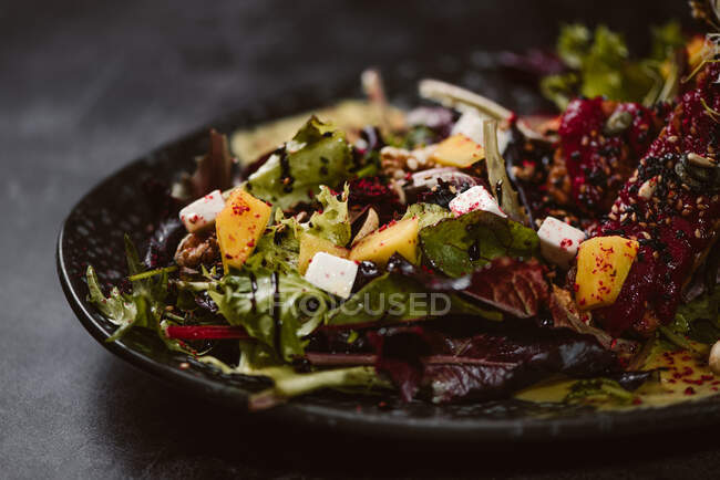 Plate with tasty vegetarian Indonesian salad with fresh mango and cashew cheese slices near soybeans and condiments covered with basil vinaigrette — Stock Photo