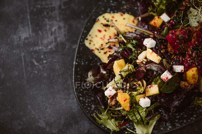 Top view of plate with tasty vegetarian Indonesian salad with fresh mango and cashew cheese slices near soybeans and condiments covered with basil vinaigrette — Stock Photo