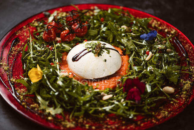 Yummy burrata cheese on cold tomato cream with arugula leaves and cherry tomatoes with truffles and peanuts — Stock Photo