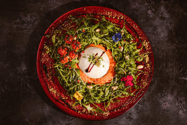 Overhead view of yummy burrata cheese on cold tomato cream with arugula leaves and cherry tomatoes with truffles and peanuts — Stock Photo