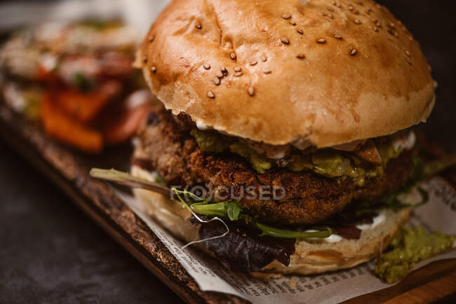 Close up de hambúrguer gostoso com pato vegetariano e shiitakes grelhados entre pães perto de batata-doce e fatias de cenoura com molho de álioli no fundo escuro — Fotografia de Stock