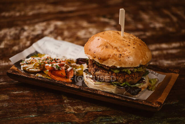 Leckerer Burger mit vegetarischem Patty und gegrillten Shiitakes zwischen Brötchen in der Nähe von Süßkartoffel- und Karottenscheiben mit Alioli-Sauce auf dunklem Hintergrund — Stockfoto