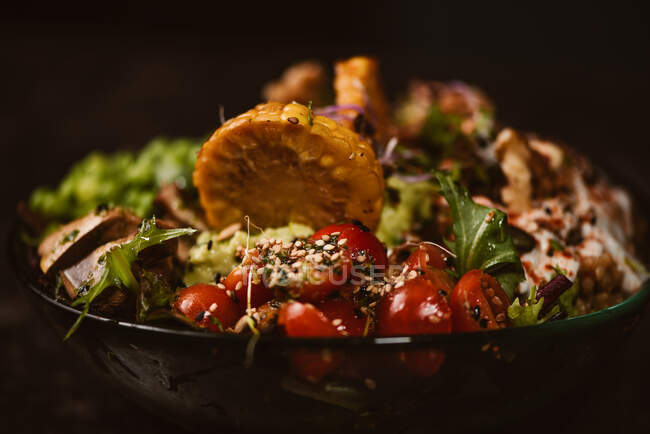 Tigela de saborosas fatias de batata-doce com tomates cereja perto de ervilhas verdes e sementes de gergelim no fundo escuro — Fotografia de Stock