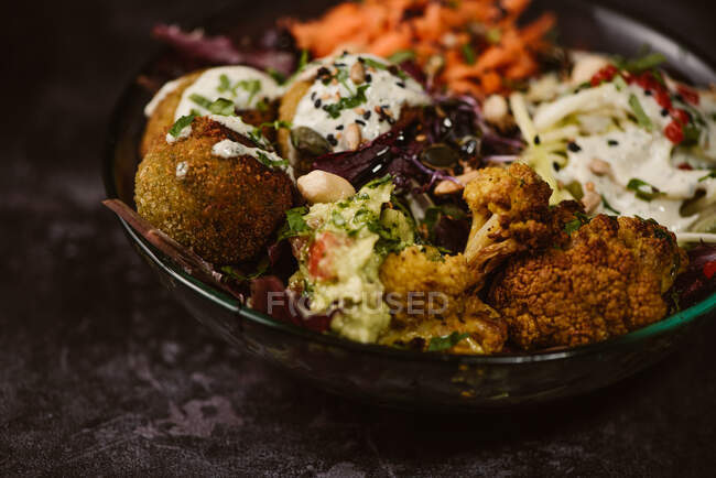 Bowl of tasty cauliflower near zucchini noodles with carrot slices covered with yogurt mint sauce — Stock Photo