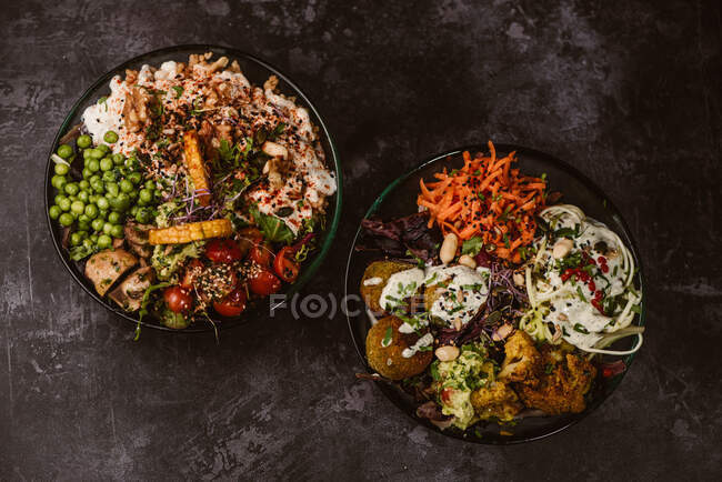 Platos vegetarianos orgánicos apetitosos con verduras variadas en mesa oscura rústica - foto de stock